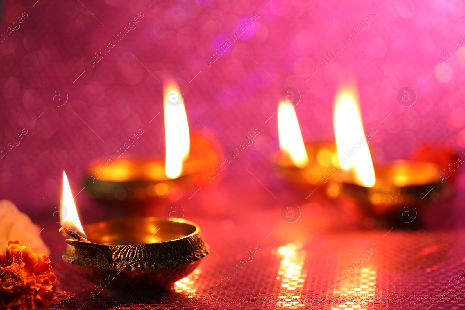 Photo of Diwali celebration. Diya lamps and beautiful flowers on color background, closeup. Space for text