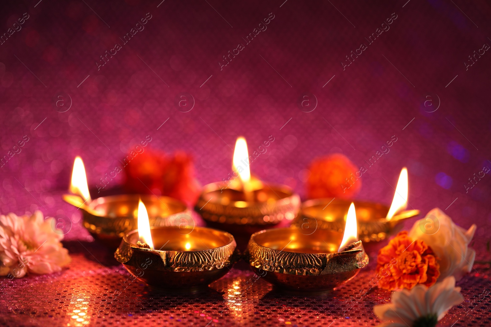 Photo of Diwali celebration. Diya lamps and beautiful flowers on color background, closeup