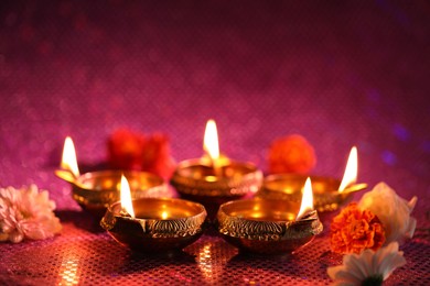 Photo of Diwali celebration. Diya lamps and beautiful flowers on color background, closeup