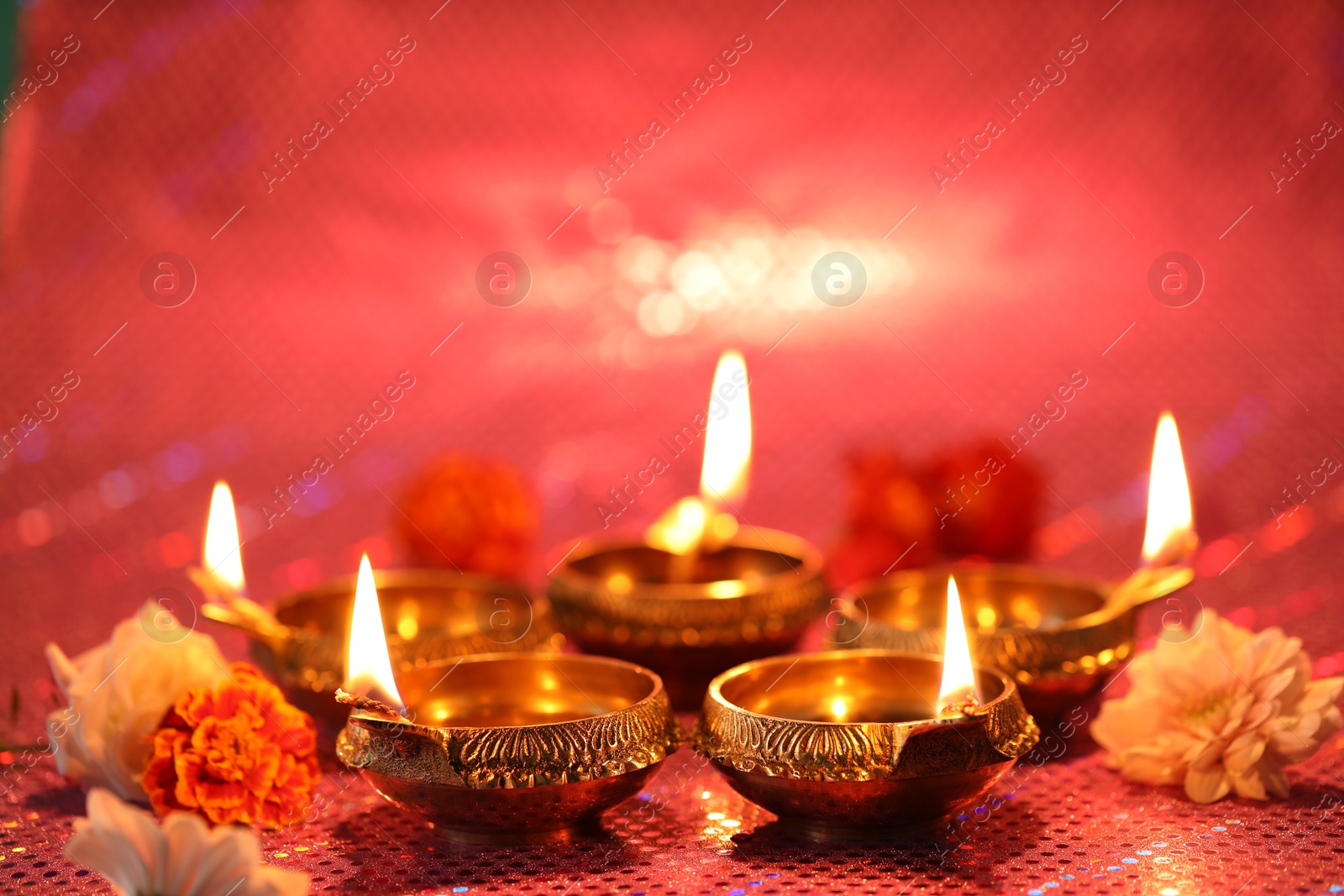 Photo of Diwali celebration. Diya lamps and beautiful flowers on color background, closeup