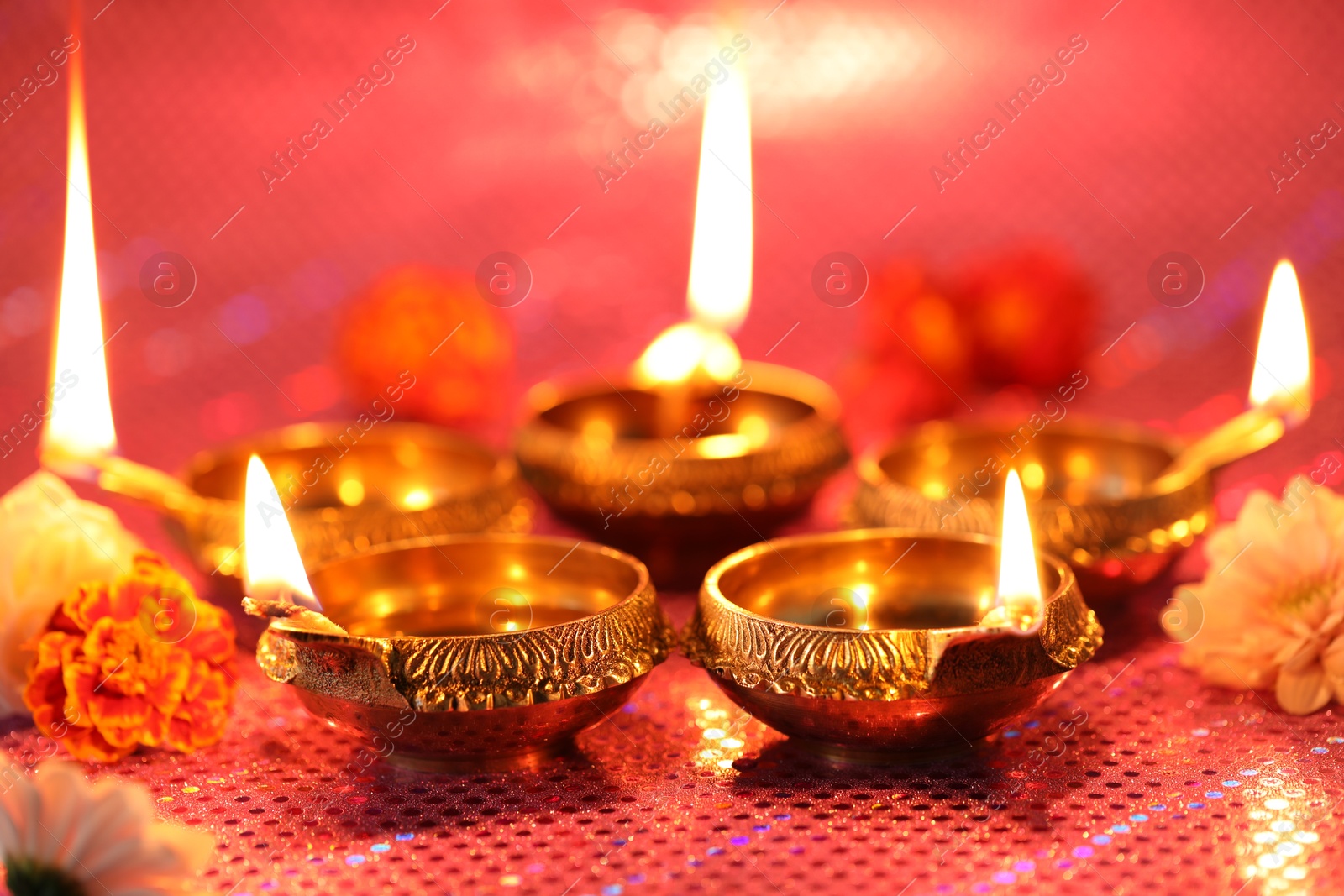 Photo of Diwali celebration. Diya lamps and beautiful flowers on color background, closeup