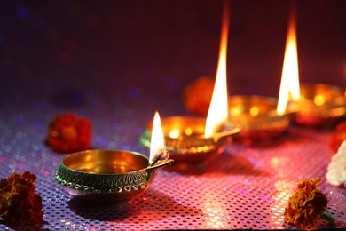 Photo of Diwali celebration. Diya lamps and beautiful flowers on color background, closeup