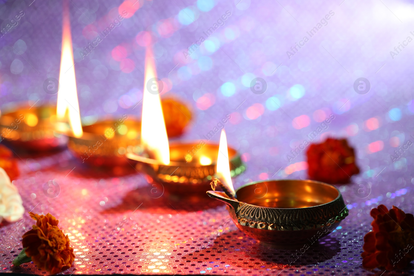 Photo of Diwali celebration. Diya lamps and beautiful flowers on color background, closeup