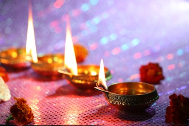 Photo of Diwali celebration. Diya lamps and beautiful flowers on color background, closeup