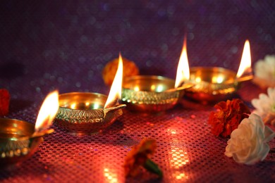 Photo of Diwali celebration. Diya lamps and beautiful flowers on color background, closeup