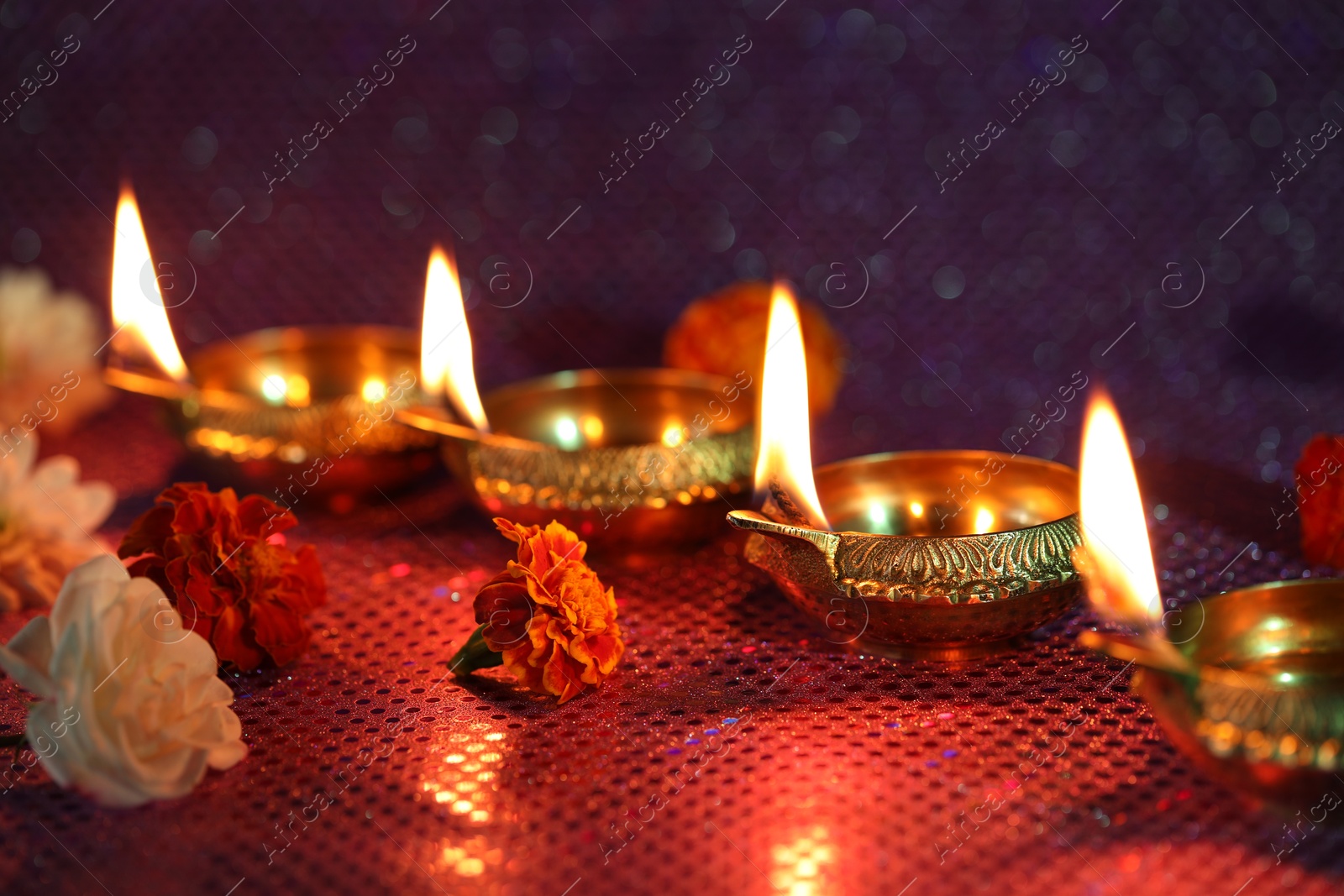 Photo of Diwali celebration. Diya lamps and beautiful flowers on color background, closeup