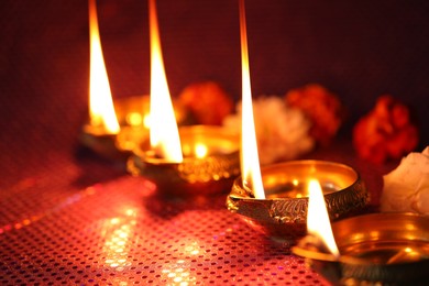 Photo of Diwali celebration. Diya lamps and beautiful flowers on color background, closeup