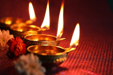 Photo of Diwali celebration. Diya lamps and beautiful flowers on color background, closeup