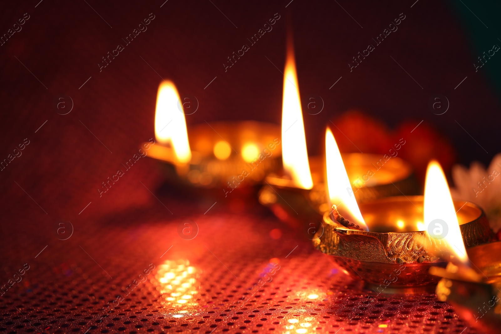 Photo of Diwali celebration. Diya lamps and beautiful flowers on color background, closeup