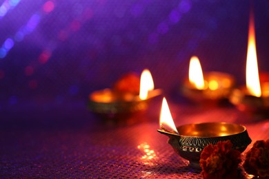 Photo of Diwali celebration. Diya lamps and beautiful flowers on color background, closeup. Space for text