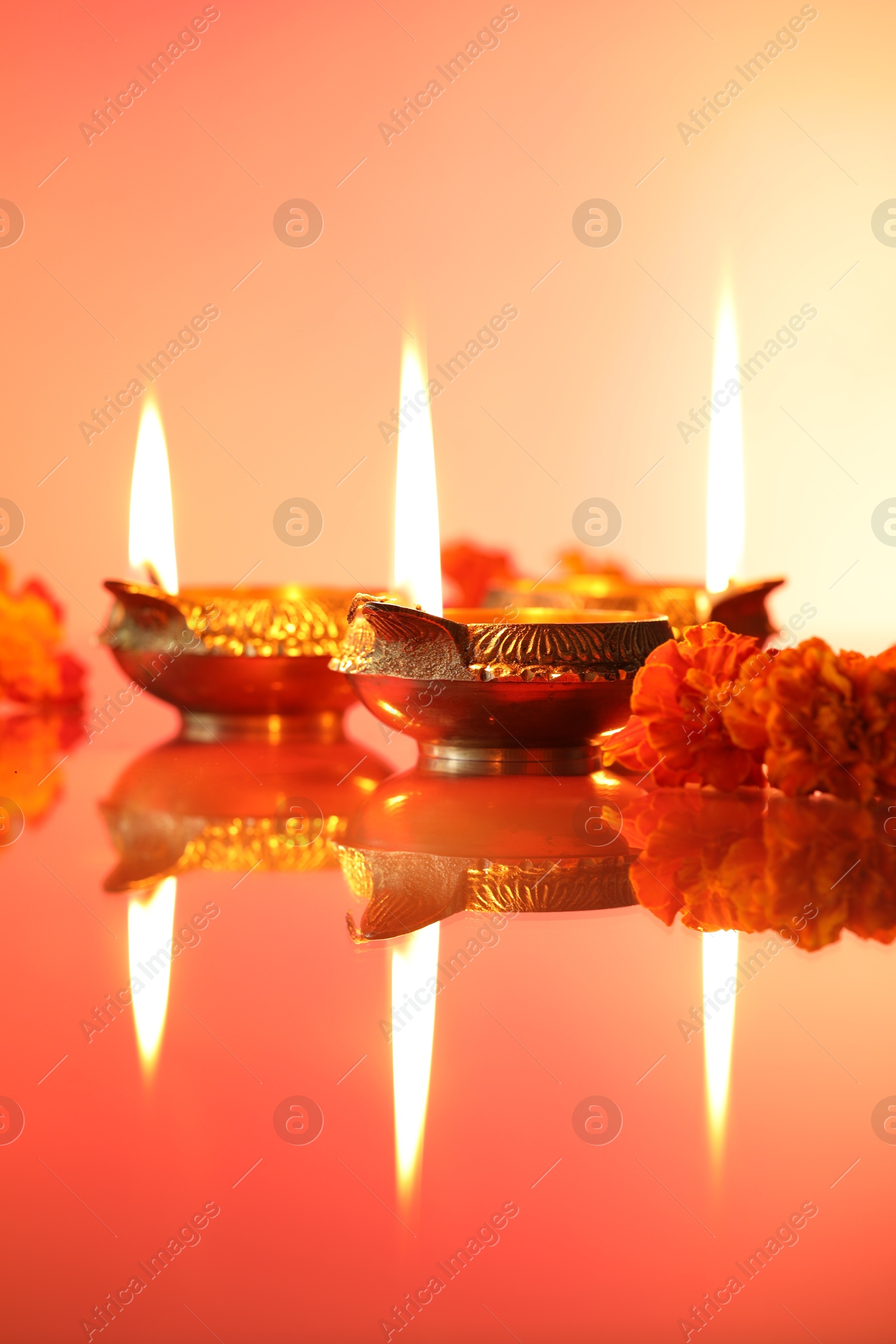 Photo of Diwali celebration. Diya lamps and beautiful flowers on color background, closeup