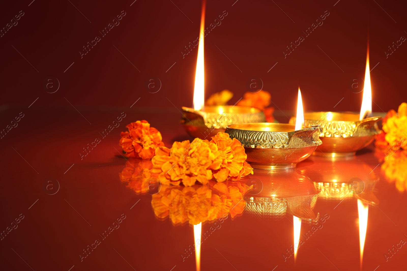 Photo of Diwali celebration. Diya lamps and beautiful flowers on color background, closeup