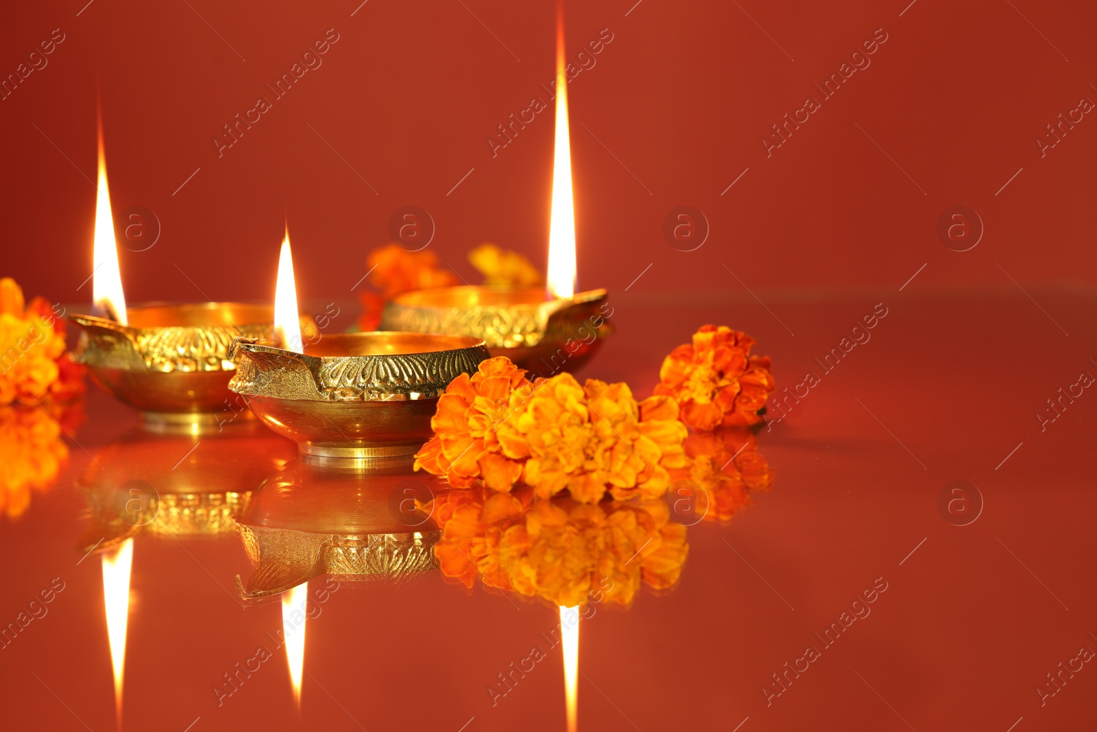 Photo of Diwali celebration. Diya lamps and beautiful flowers on color background, closeup