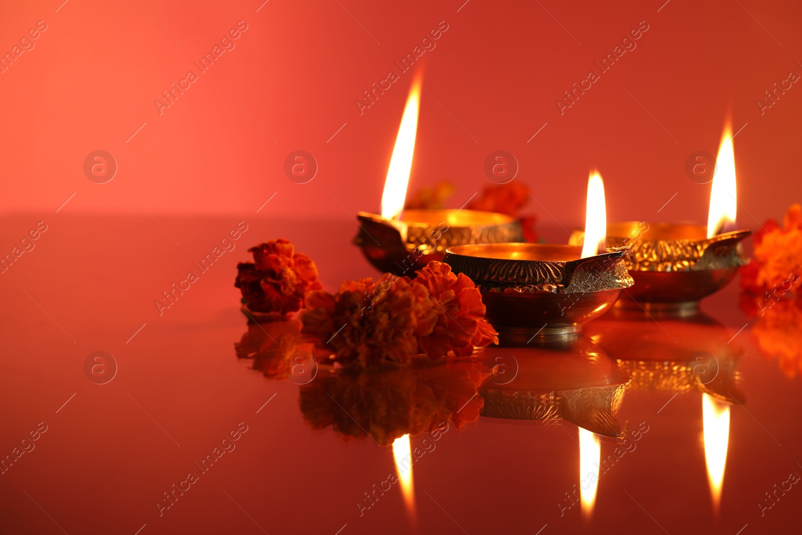 Photo of Diwali celebration. Diya lamps and beautiful flowers on color background, closeup. Space for text