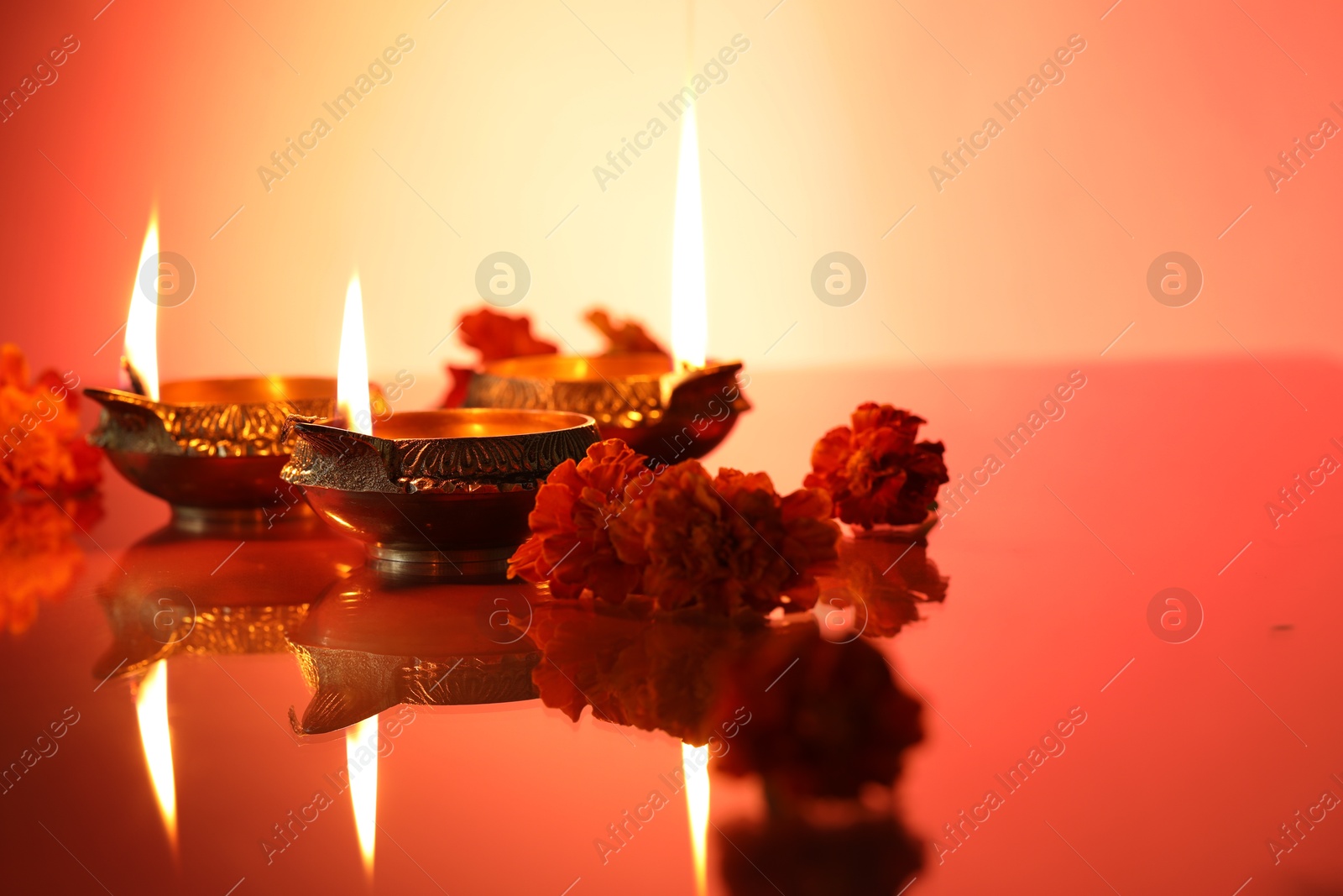 Photo of Diwali celebration. Diya lamps and beautiful flowers on color background, closeup. Space for text