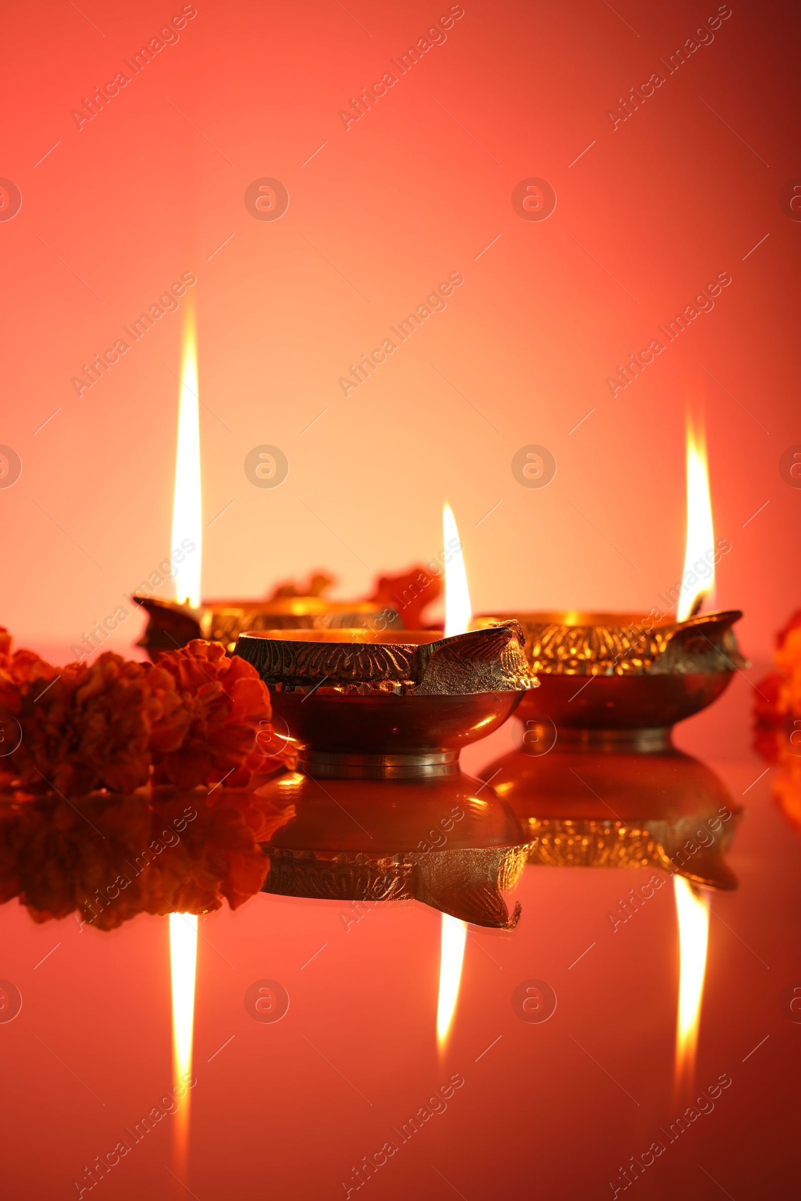 Photo of Diwali celebration. Diya lamps and beautiful flowers on color background, closeup