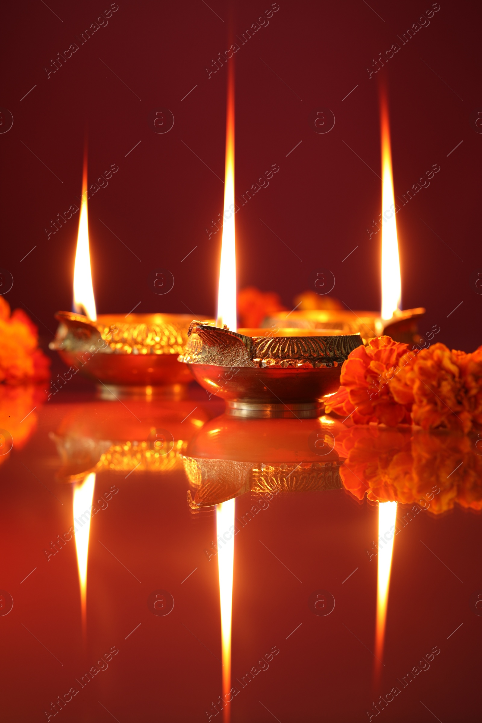 Photo of Diwali celebration. Diya lamps and beautiful flowers on color background, closeup