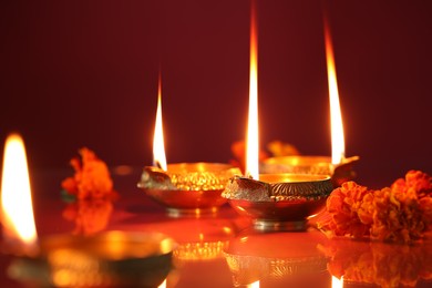 Photo of Diwali celebration. Diya lamps and beautiful flowers on color background, closeup