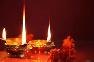 Photo of Diwali celebration. Diya lamps and beautiful flowers on color background, closeup