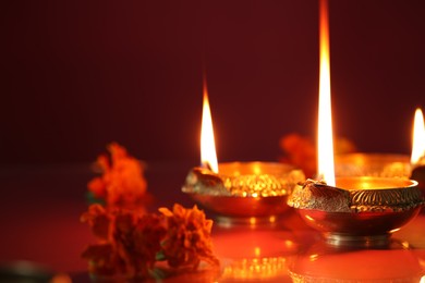 Photo of Diwali celebration. Diya lamps and beautiful flowers on color background, closeup