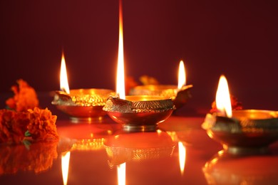 Photo of Diwali celebration. Diya lamps and beautiful flowers on color background, closeup