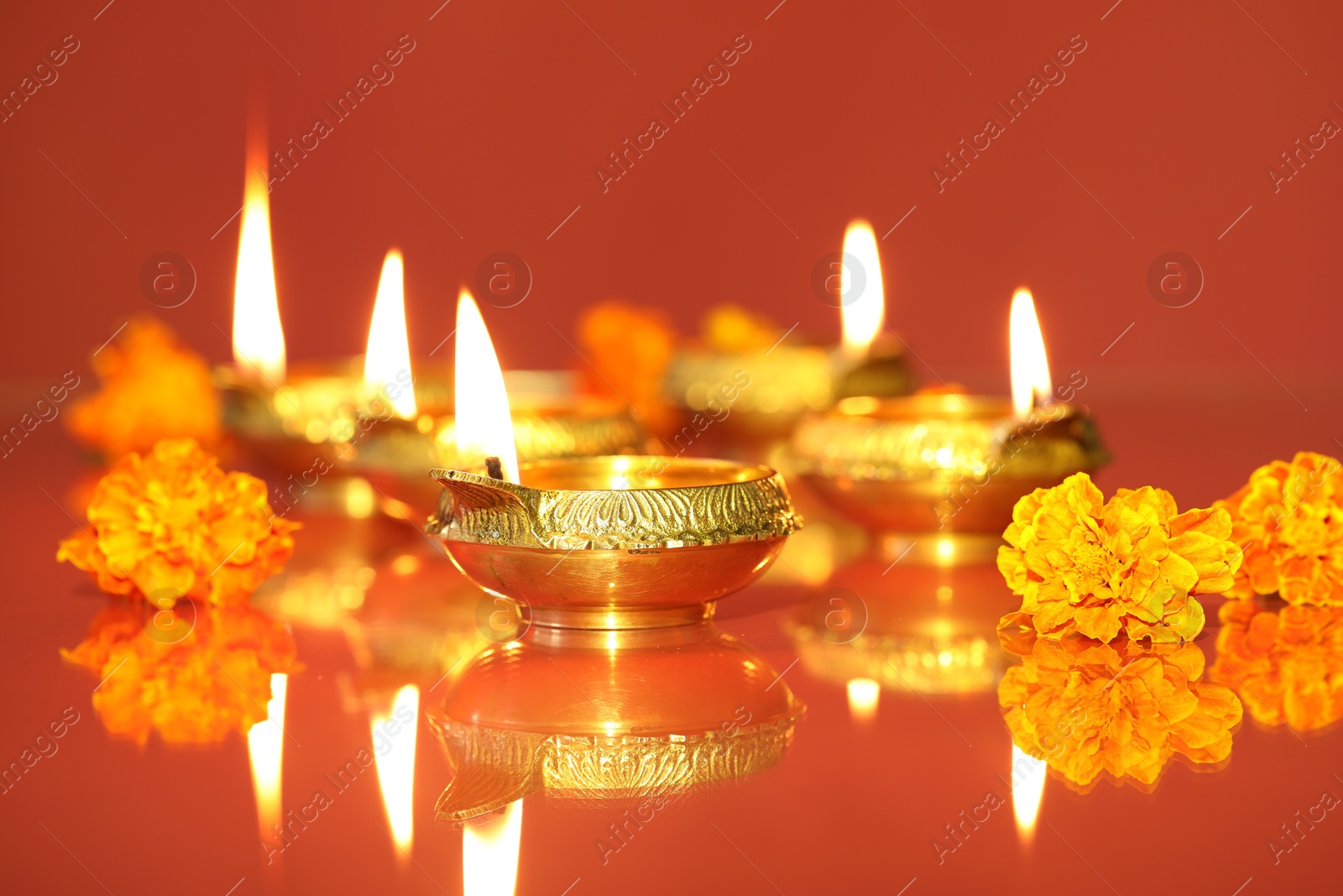 Photo of Diwali celebration. Diya lamps and beautiful flowers on color background, closeup