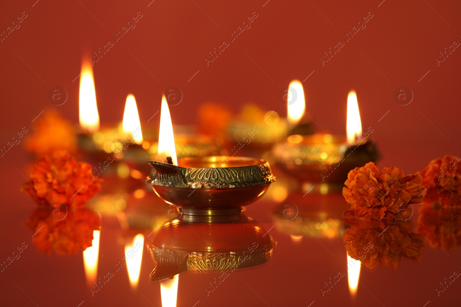 Photo of Diwali celebration. Diya lamps and beautiful flowers on color background, closeup