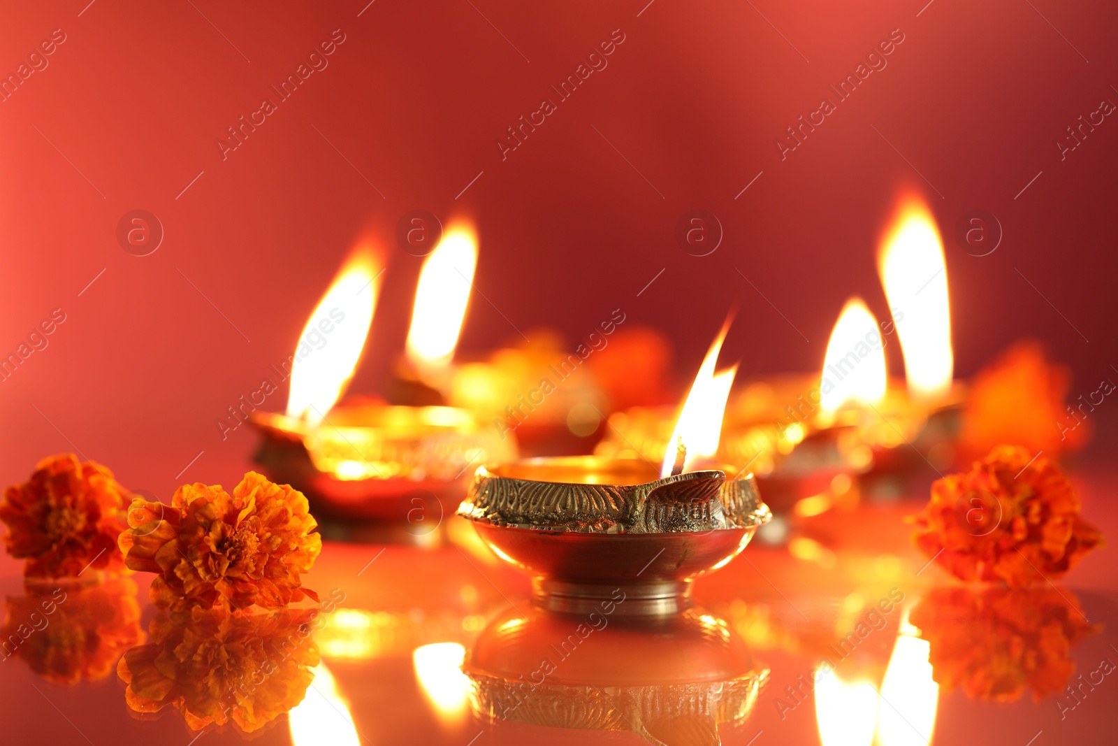 Photo of Diwali celebration. Diya lamps and beautiful flowers on color background, closeup