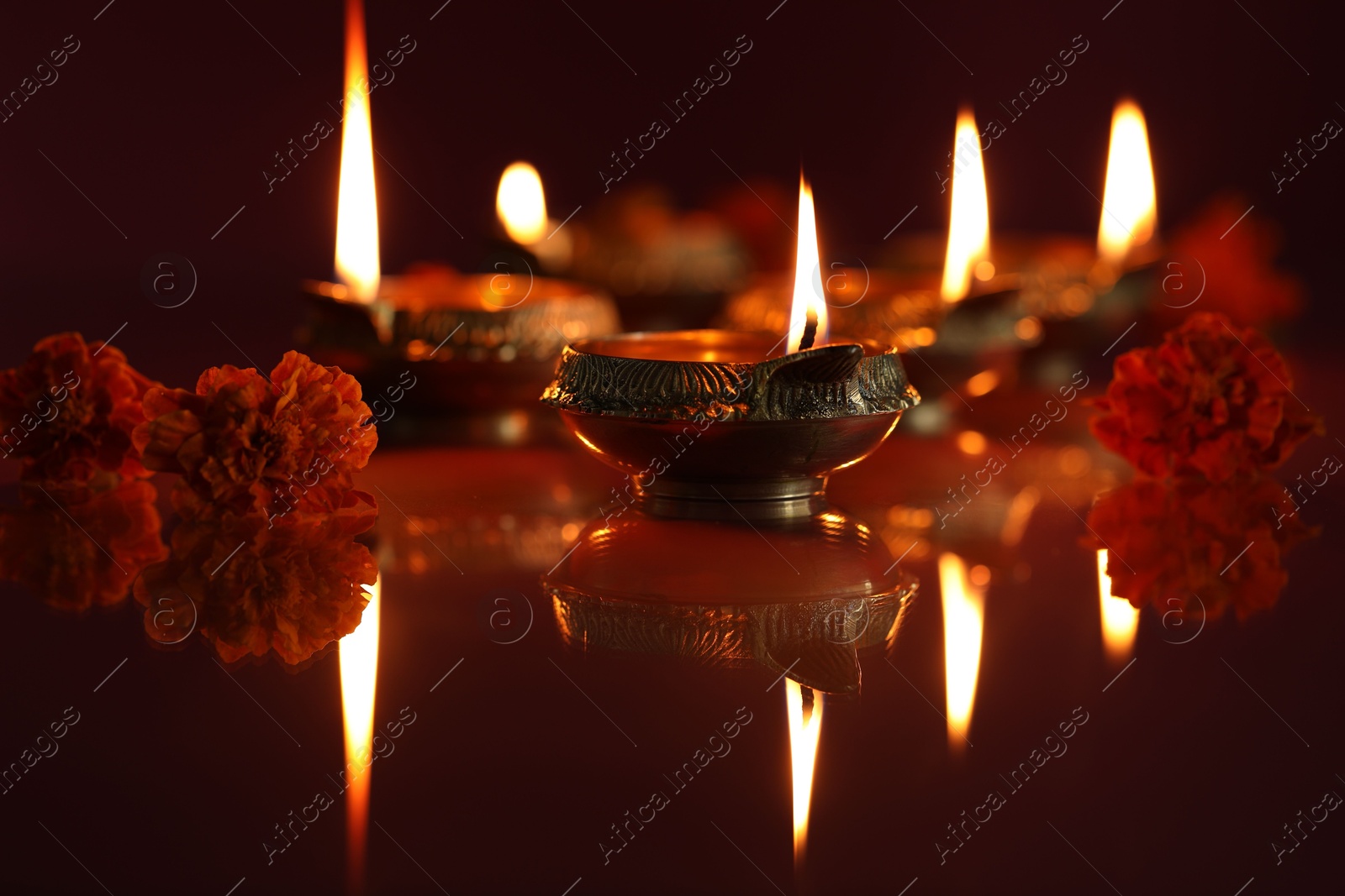 Photo of Diwali celebration. Diya lamps and beautiful flowers on dark background, closeup