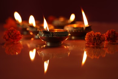 Photo of Diwali celebration. Diya lamps and beautiful flowers on color background, closeup