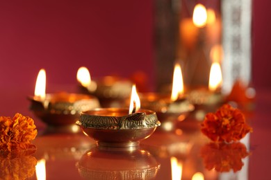 Photo of Diwali celebration. Diya lamps and beautiful flowers on color background, closeup