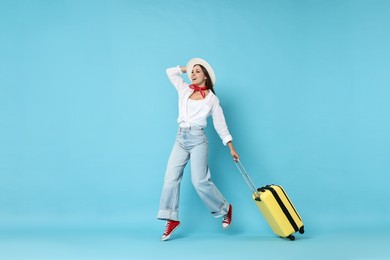 Photo of Happy young woman with suitcase on light blue background