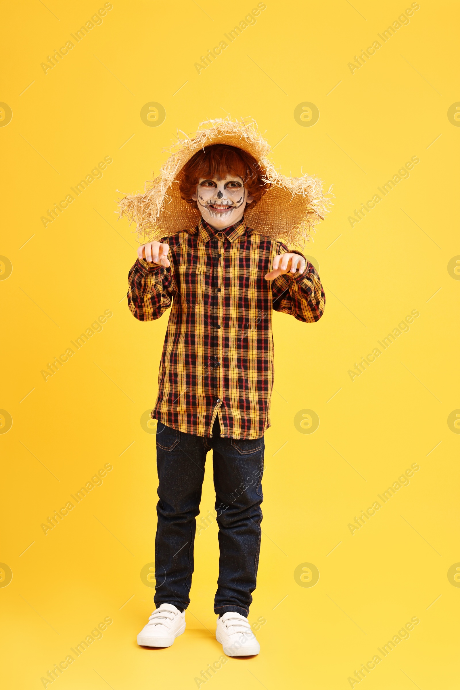 Photo of Funny boy dressed like scarecrow on yellow background. Halloween celebration