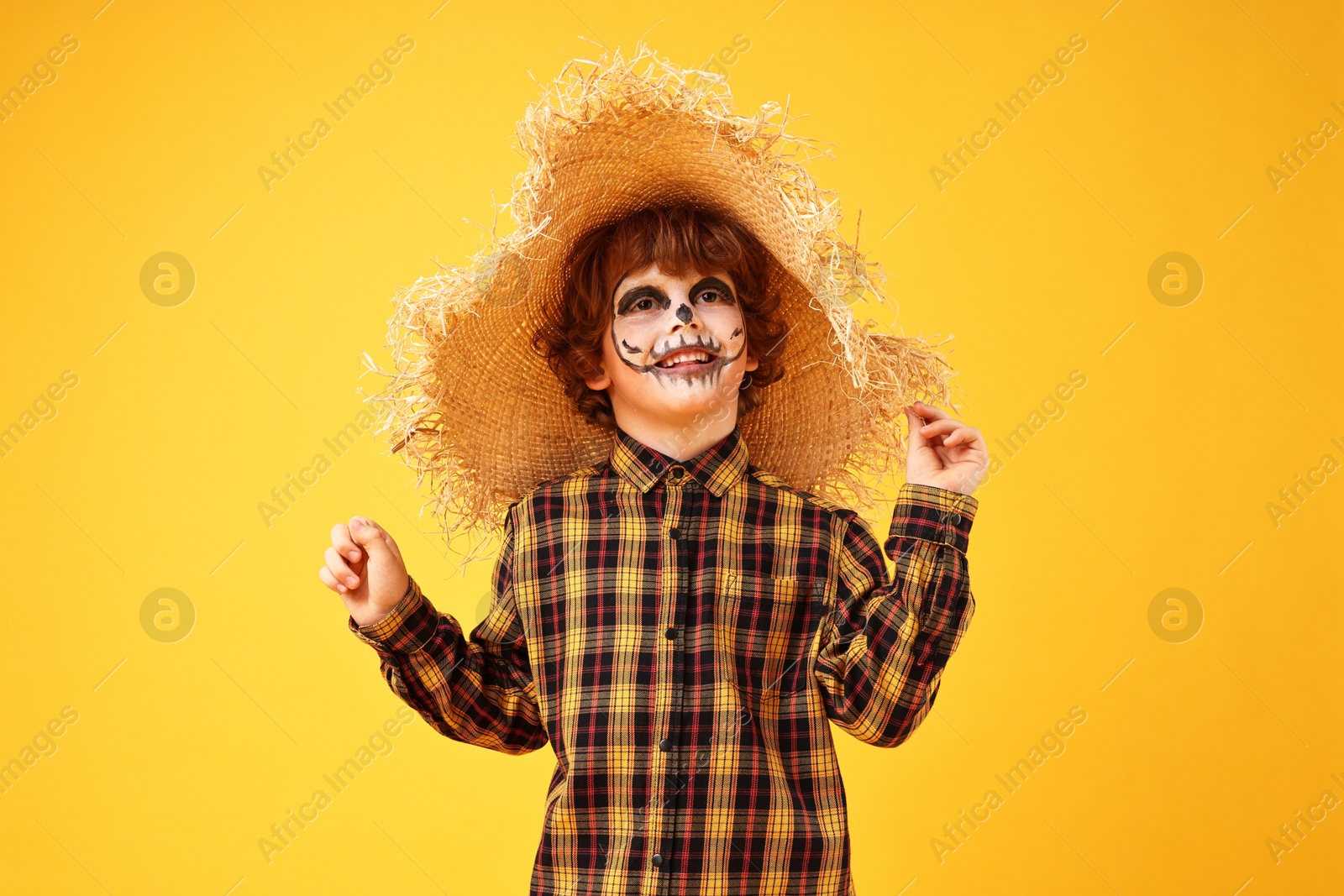 Photo of Funny boy dressed like scarecrow on yellow background. Halloween celebration