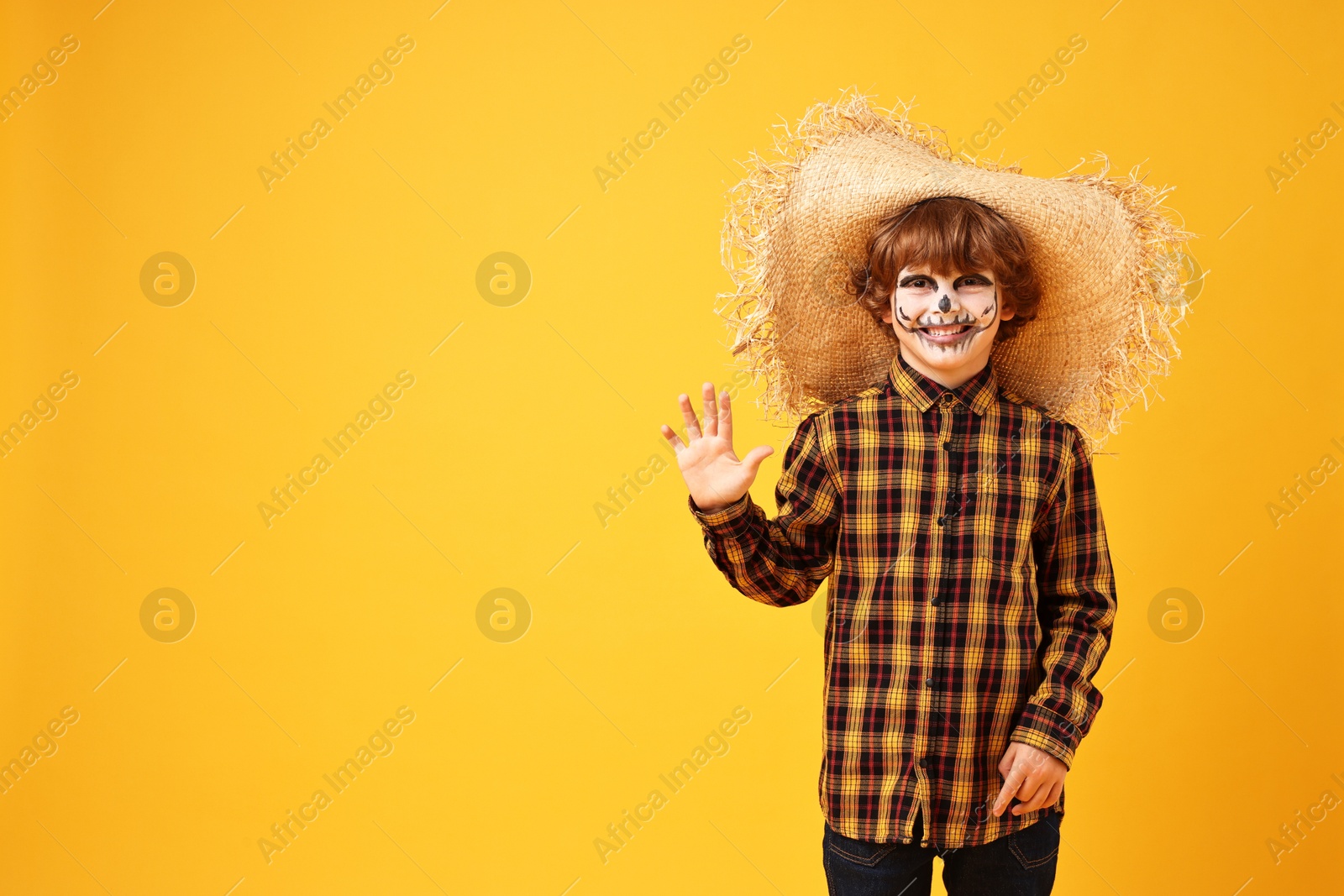 Photo of Funny boy dressed like scarecrow on yellow background, space for text. Halloween celebration