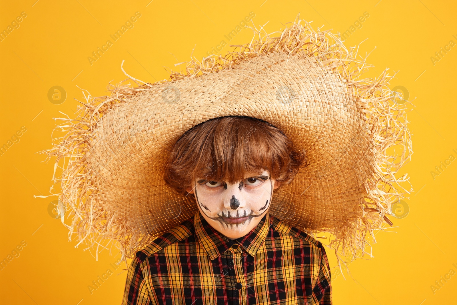 Photo of Funny boy dressed like scarecrow on yellow background. Halloween celebration