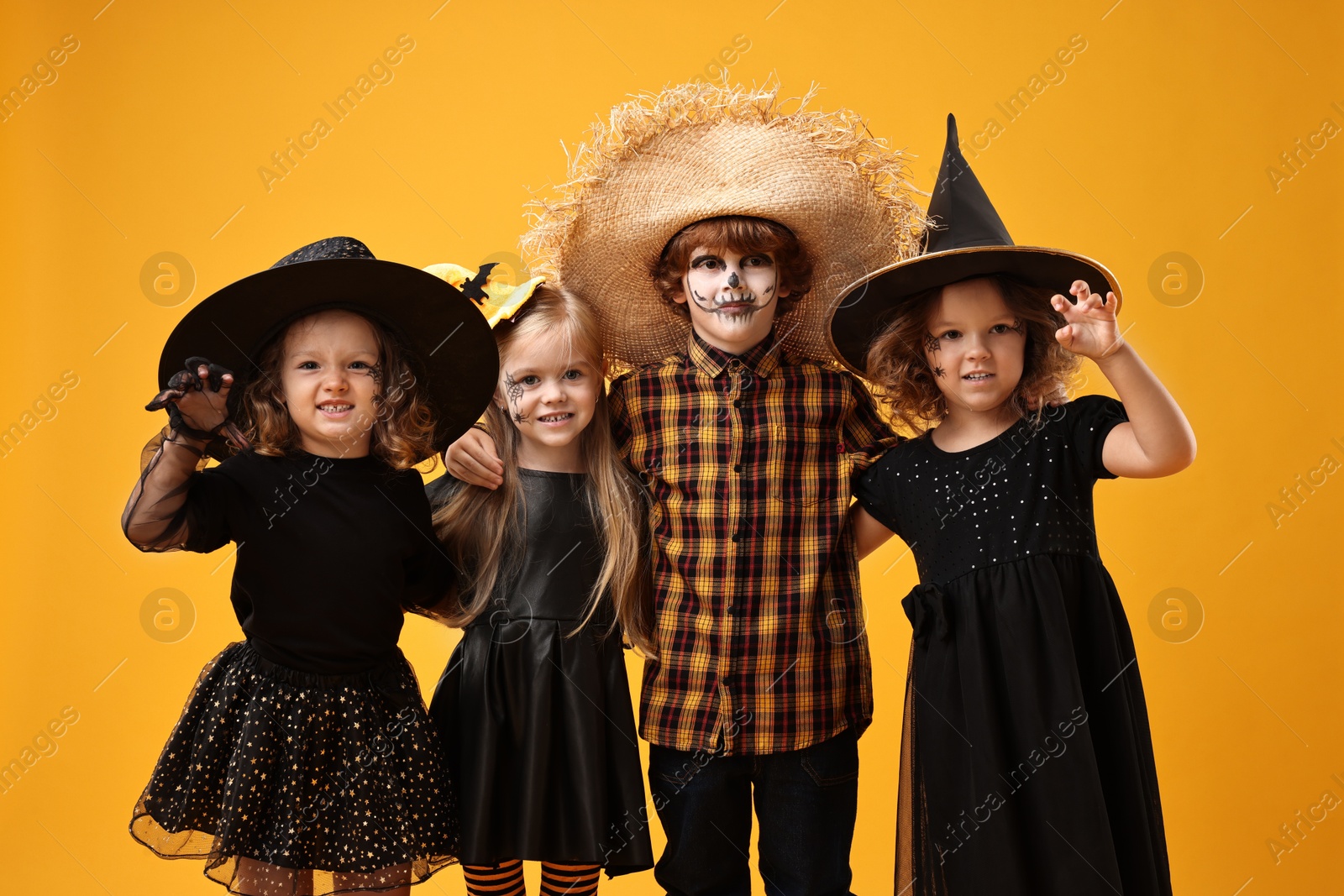 Photo of Cute children wearing Halloween costumes on orange background