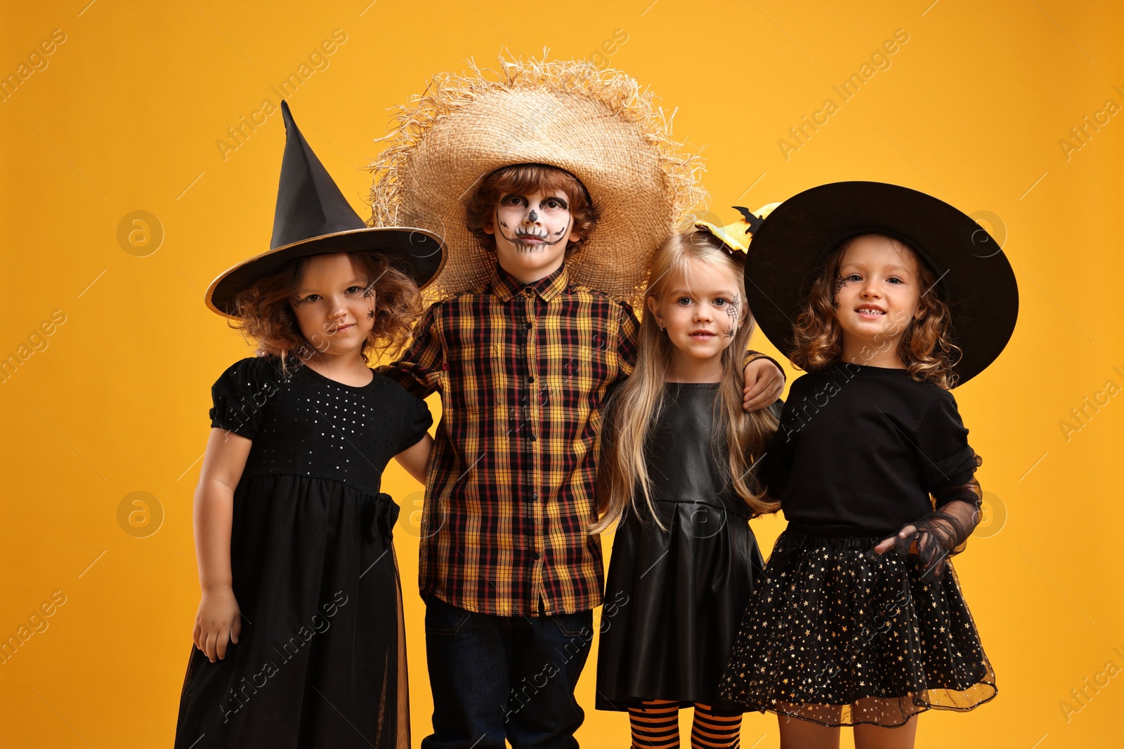 Photo of Cute children wearing Halloween costumes on orange background