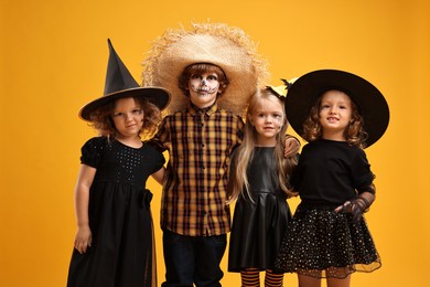 Photo of Cute children wearing Halloween costumes on orange background