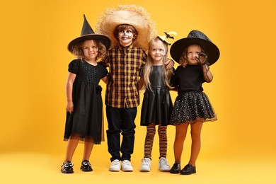 Photo of Cute children wearing Halloween costumes on orange background