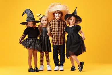 Photo of Cute children wearing Halloween costumes on orange background