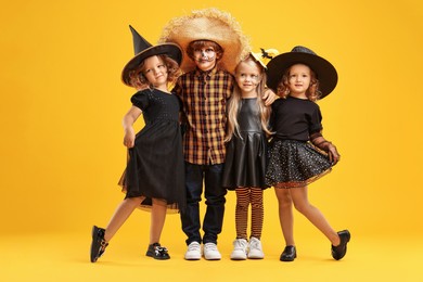 Cute children wearing Halloween costumes on orange background