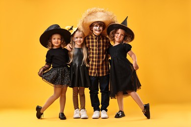 Cute children wearing Halloween costumes on orange background