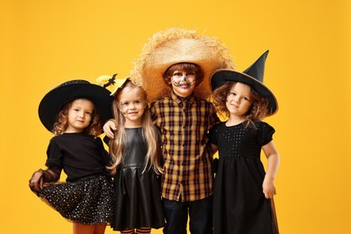 Cute children wearing Halloween costumes on orange background