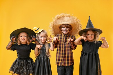 Photo of Cute children wearing Halloween costumes on orange background