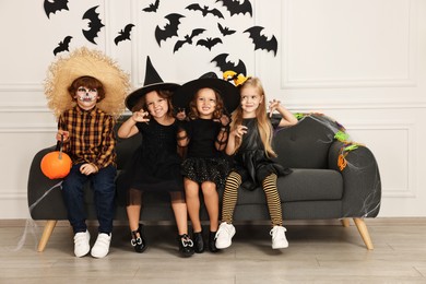 Photo of Cute children with pumpkin bucket wearing costumes indoors. Halloween celebration