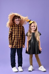 Photo of Cute children wearing costumes on violet background. Halloween celebration