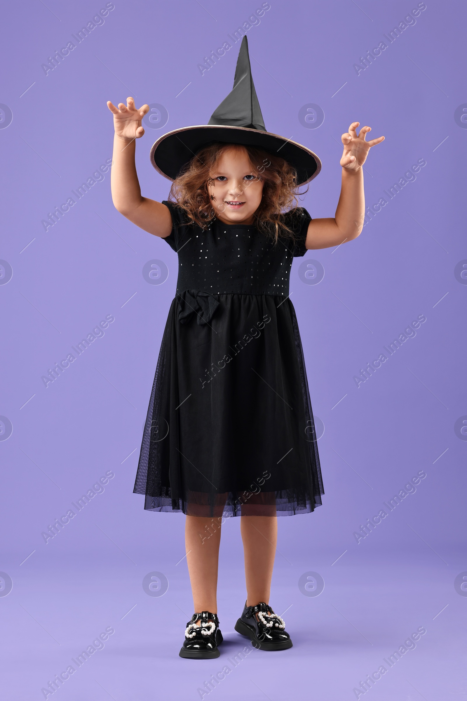 Photo of Funny girl dressed like witch for Halloween celebration on violet background