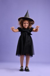 Photo of Funny girl dressed like witch for Halloween celebration on violet background