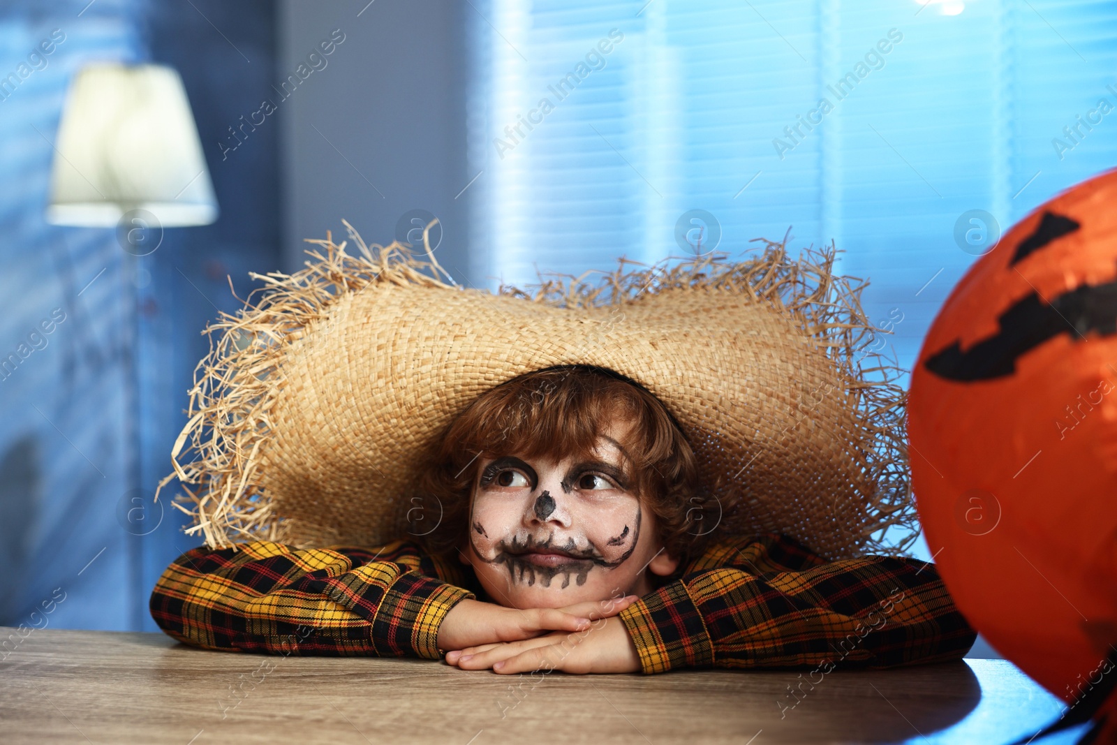 Photo of Cute boy dressed like scarecrow indoors at night. Halloween celebration